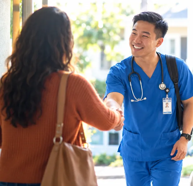 A visiting clinician greeting a family member at the door